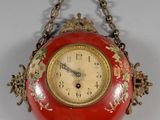 a red clock hanging from a chain on a wall
