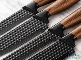 four knives are lined up on a marble counter top