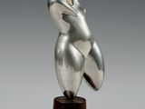 une sculpture en argent représentant une tête de femme posée sur un socle en bois