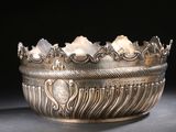 un bol en argent richement décoré posé sur une surface noire, avec un fond noir