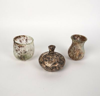 trois petits vases sont posés sur une surface blanche, devant un fond blanc