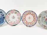 four plates with different designs are lined up on a white surface