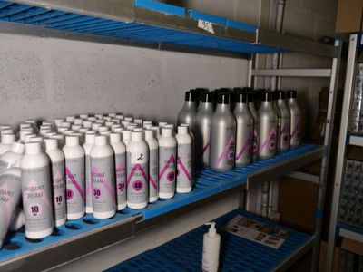 de nombreux flacons de produits capillaires posés sur une étagère dans une pièce