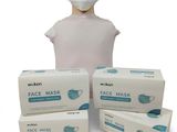 a person wearing a face mask next to three boxes of face masks