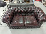 a brown leather couch sitting in a room with other furniture in the background