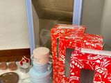 a red box with white flowers on it next to a blue box with a pink lid and a red box with white flowers on it next to a blue