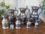 a lot of silver vases sitting on a wooden table