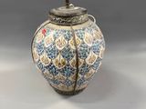 a blue and white vase with a light on top of it