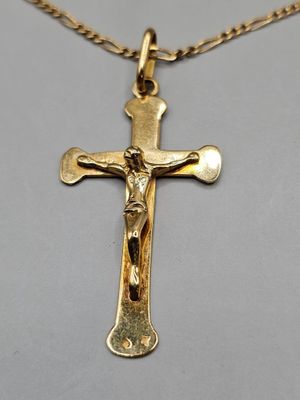 un gros plan d'une croix suspendue à une chaîne en or, posée sur une table