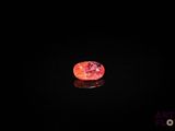 un diamant rouge sur une surface noire, dans l'obscurité