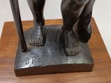 bronze statue of a man with a cane on a wooden base