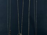 a group of four gold necklaces on a black background