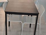 une table et des chaises dans une pièce où est accrochée une horloge au mur