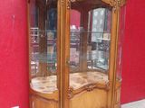 a wooden cabinet with a glass door and a red wall