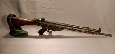 an old gun is sitting on a stand on a white surface