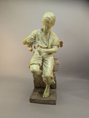 statue d'un garçon assis sur un rocher, tenant un livre