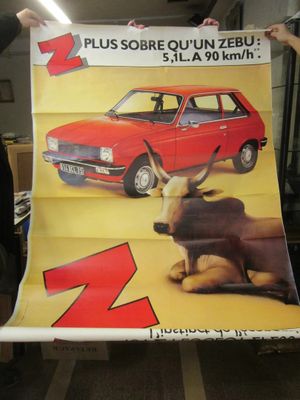Quelqu'un tient une grande affiche représentant une voiture et une vache.