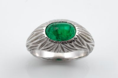a close up of a ring with a green stone in it