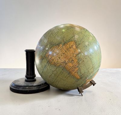 un globe vert posé sur une table à côté d'un bougeoir noir