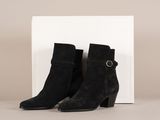 une paire de bottines noires en daim avec des boucles et une boîte blanche