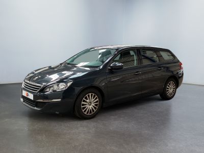 La voiture noire est garée dans une grande pièce aux murs blancs.