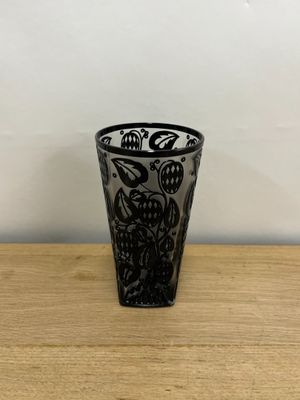 black and white shot glass on a wooden table with a white wall in the background