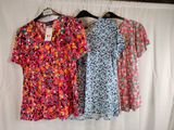 three women ' s dresses hanging on a clothes rack in front of a white backdrop