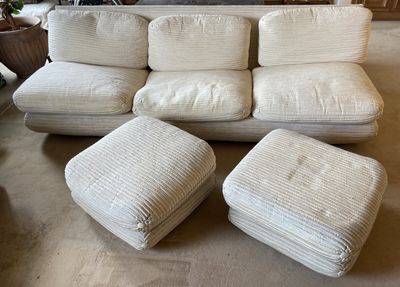 un canapé blanc et un pouf dans un salon