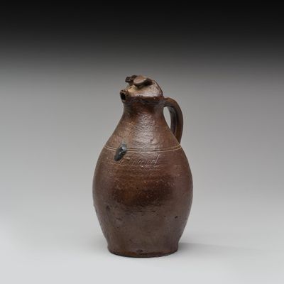 un vieux vase marron posé sur une table blanche