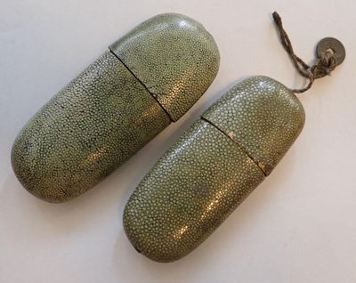 pair of green metal pill cases sitting on top of a white surface