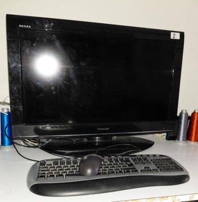 un écran d'ordinateur et un clavier posés sur un bureau