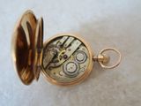 a gold pocket watch sitting on a white surface