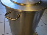 une grande casserole en métal avec un couvercle, posée sur un sol carrelé