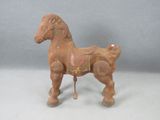 un petit cheval en bois avec une selle sur le dos
