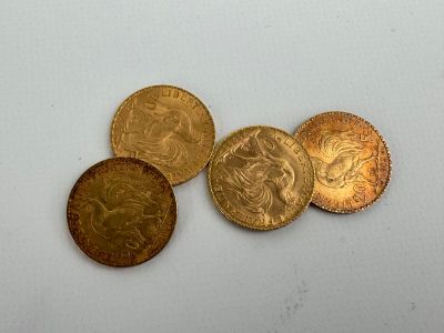 four gold coins sitting on top of each other on a white surface