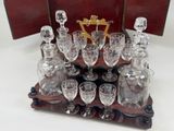 bottles and glasses on a wooden tray on a white surface