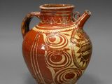 a brown vase with designs on it on a gray surface
