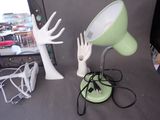 a green lamp that is on a table next to a hand