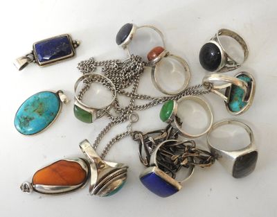 several different rings and pendants are arranged on a white surface