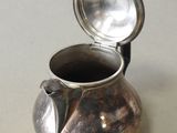 a silver pitcher with a lid sitting on a table