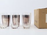 four glasses and a box of champagne sitting on a white surface