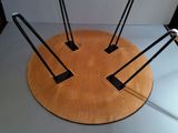 a wooden table with four black legs and a round wooden table top