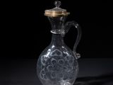 a clear glass jug with a gold lid sitting on a black surface
