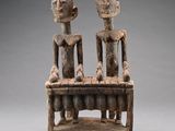 une sculpture en bois représentant deux personnes assises sur un banc