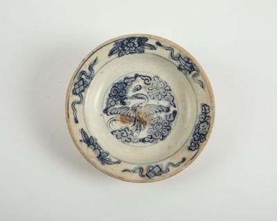 une vieille assiette bleue et blanche sur laquelle est représenté un oiseau