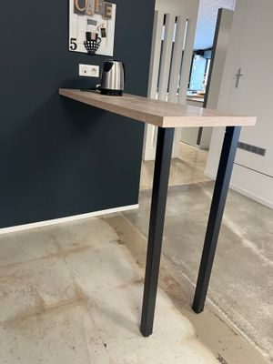 une table surmontée d'une étagère, au milieu d'une pièce