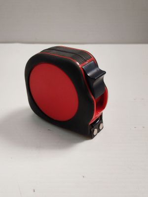 un mètre ruban rouge et noir posé sur une surface blanche
