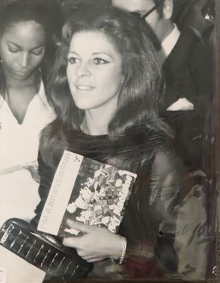 photographie en noir et blanc d'une femme tenant un livre devant un groupe de personnes