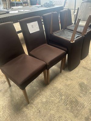 four brown chairs and a table in a room with a lot of furniture