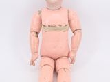 a small doll sitting on a white surface with a white background